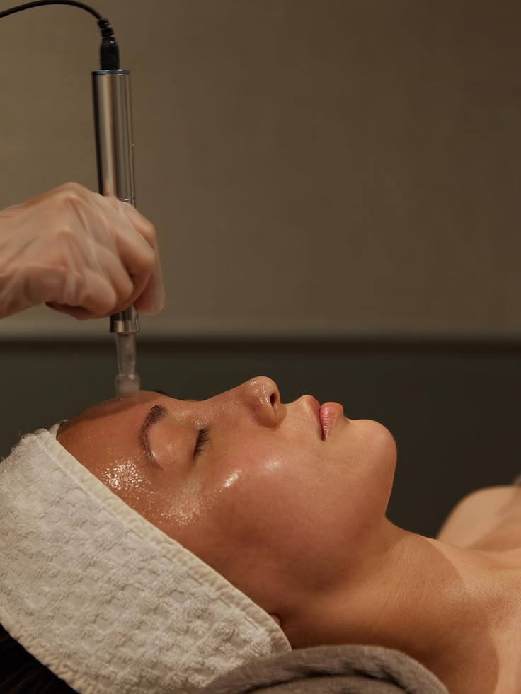 Tratamiento de microneedling en la frente, mujer recostada con vincha de toalla